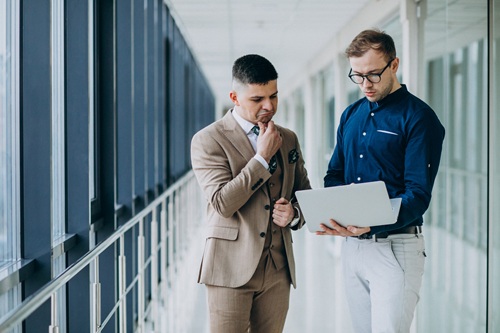 Two male colleagues at the office,standing with laptop